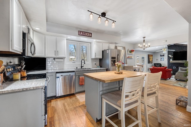 kitchen featuring stainless steel appliances, a breakfast bar, a sink, open floor plan, and a center island