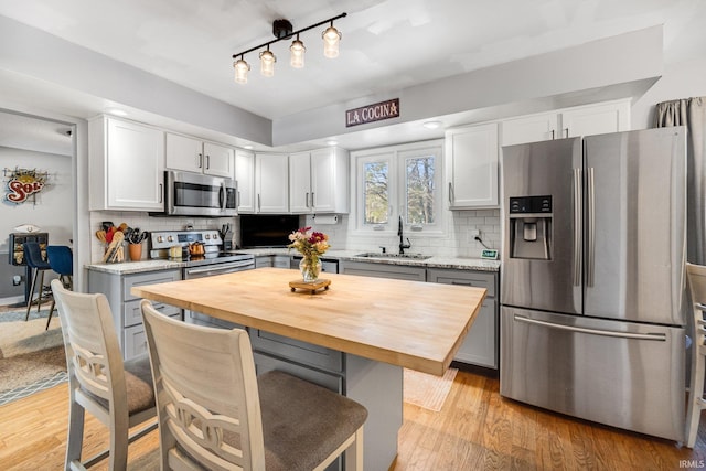 kitchen featuring stainless steel appliances, white cabinetry, a sink, and a kitchen island