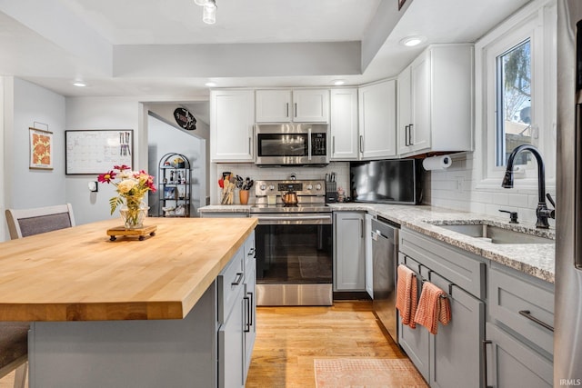 kitchen with stainless steel appliances, a center island, butcher block counters, and a sink