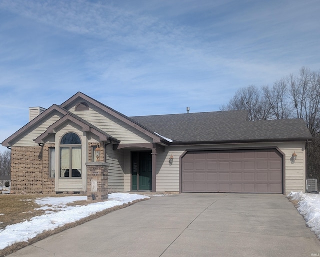 single story home featuring a shingled roof, concrete driveway, a chimney, an attached garage, and brick siding