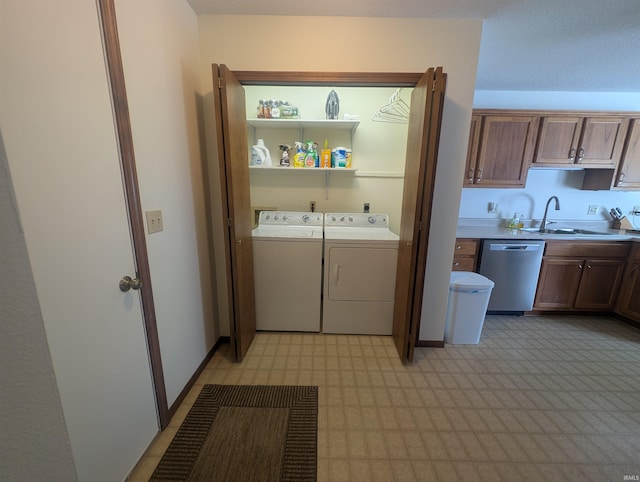 clothes washing area featuring laundry area, separate washer and dryer, a sink, baseboards, and light floors