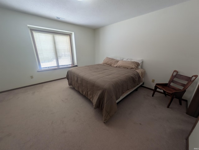 bedroom with carpet floors, visible vents, a textured ceiling, and baseboards