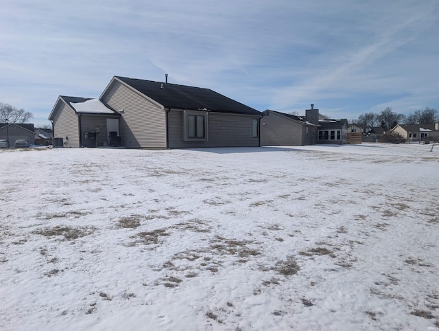 snow covered rear of property with a garage and central air condition unit