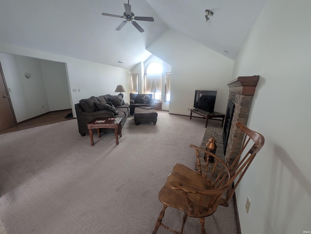 living area with a fireplace with raised hearth, high vaulted ceiling, a ceiling fan, and light colored carpet