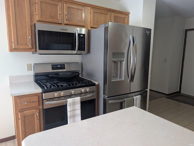 kitchen with brown cabinets, stainless steel appliances, and light countertops