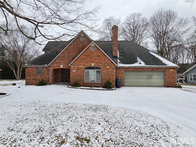 traditional home with brick siding, a chimney, and an attached garage