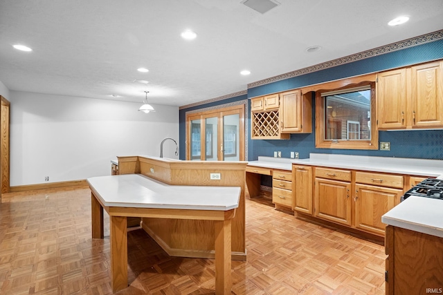 kitchen with recessed lighting, light countertops, hanging light fixtures, built in study area, and an island with sink