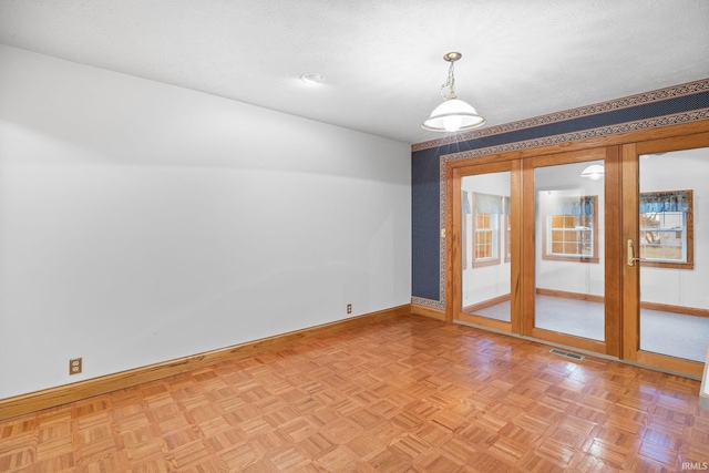 unfurnished room with a textured ceiling, visible vents, and baseboards