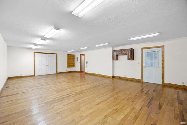 spare room with light wood-style flooring, baseboards, and a textured ceiling