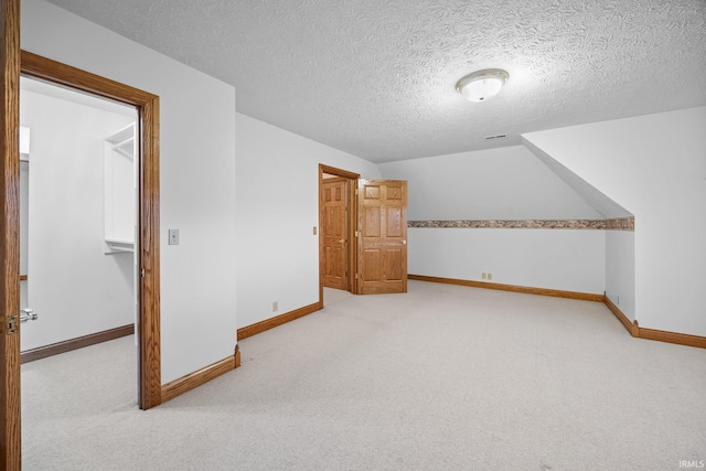 bonus room with baseboards and light colored carpet