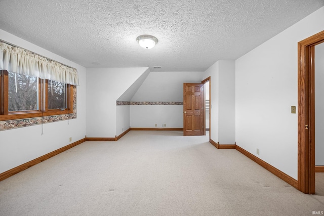 bonus room featuring light carpet, baseboards, and a textured ceiling