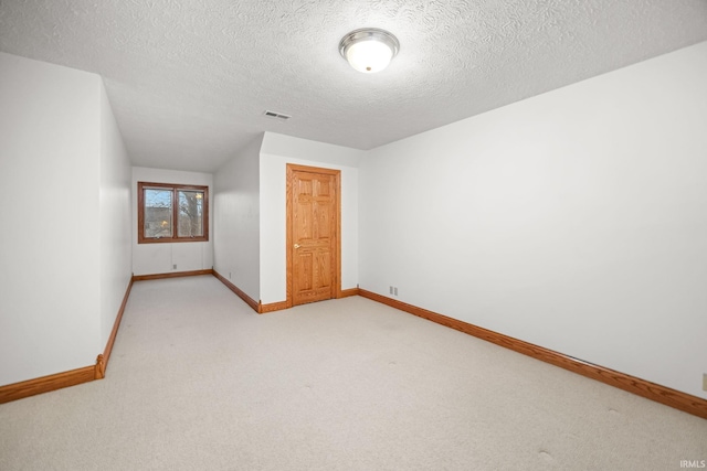 interior space with visible vents, light carpet, baseboards, and a textured ceiling