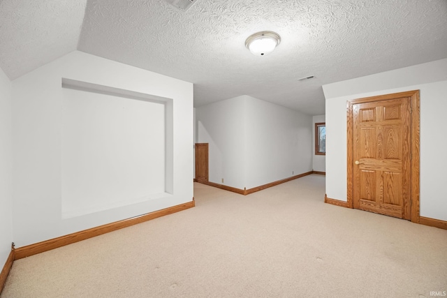 additional living space with lofted ceiling, light carpet, a textured ceiling, and baseboards