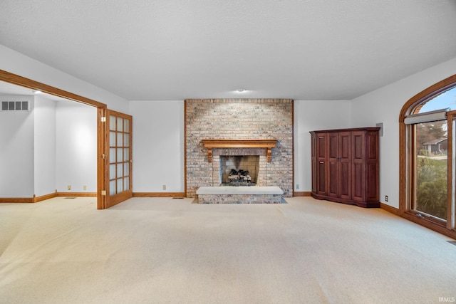 unfurnished living room with light carpet, a brick fireplace, and visible vents