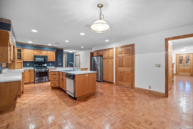 kitchen featuring a kitchen island with sink, stainless steel appliances, a sink, hanging light fixtures, and light countertops