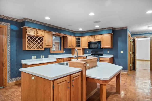 kitchen featuring black microwave, a kitchen island with sink, light countertops, range with gas cooktop, and glass insert cabinets