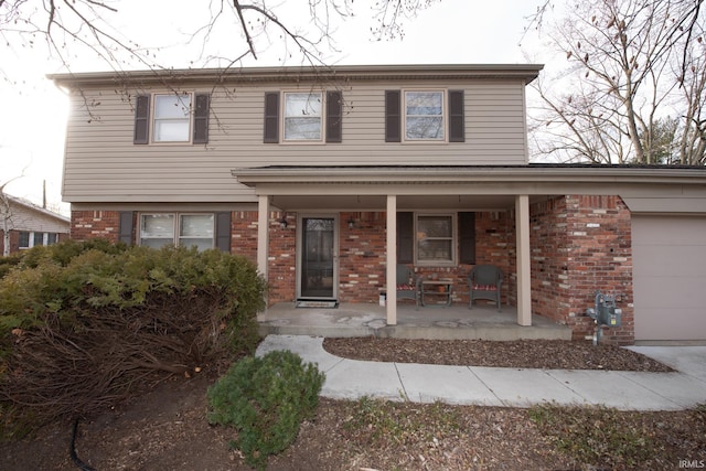 traditional-style house featuring covered porch, brick siding, and a garage