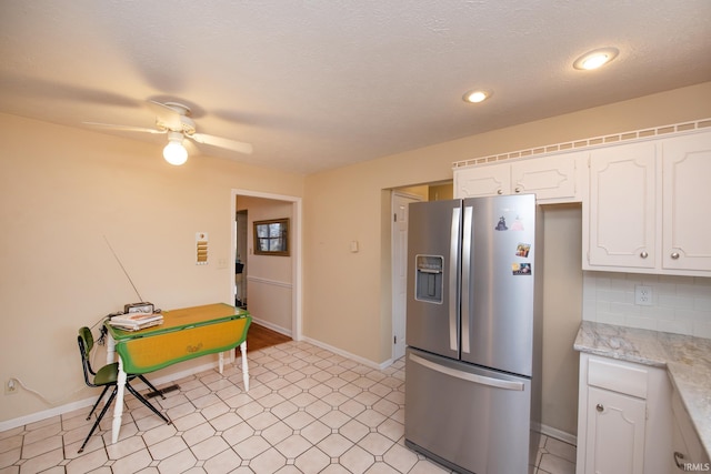 kitchen featuring baseboards, decorative backsplash, white cabinets, stainless steel fridge with ice dispenser, and light countertops