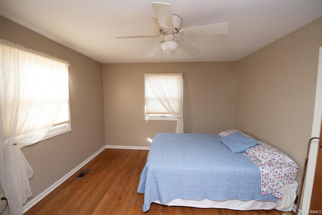 bedroom with visible vents, ceiling fan, baseboards, and wood finished floors