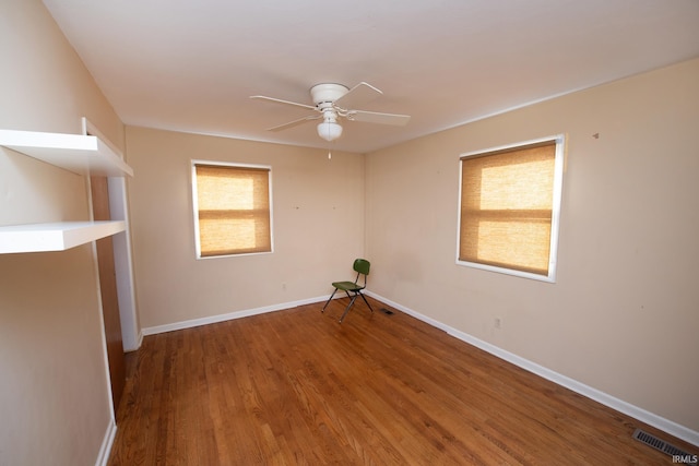 spare room with a ceiling fan, visible vents, baseboards, and wood finished floors