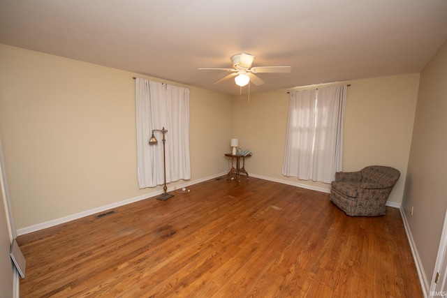 unfurnished room with baseboards, visible vents, a ceiling fan, and wood finished floors