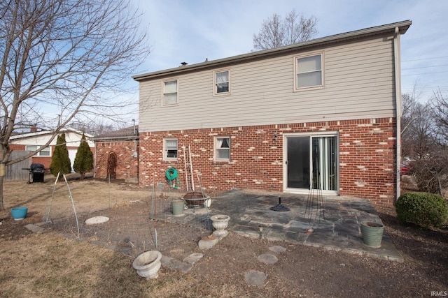 rear view of property with a patio area, a fire pit, and brick siding