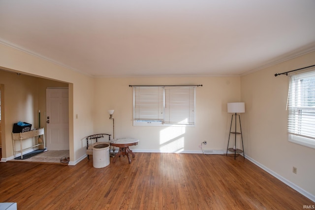 spare room featuring crown molding, baseboards, and wood finished floors