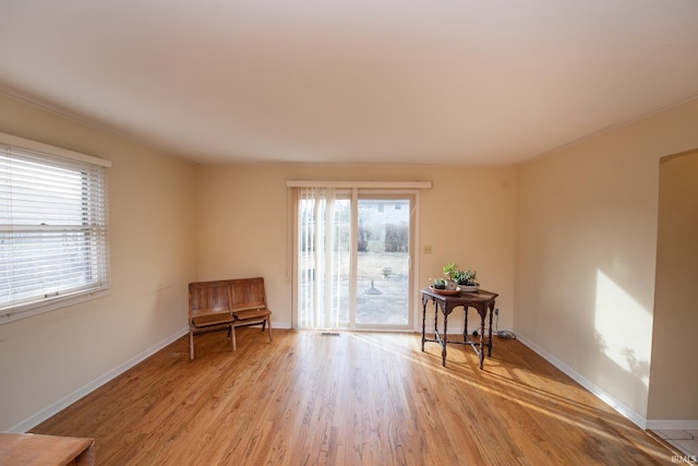 sitting room featuring a wealth of natural light, light wood-type flooring, and baseboards