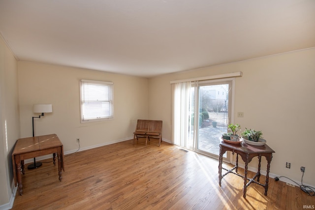 living area featuring a wealth of natural light, baseboards, and light wood finished floors