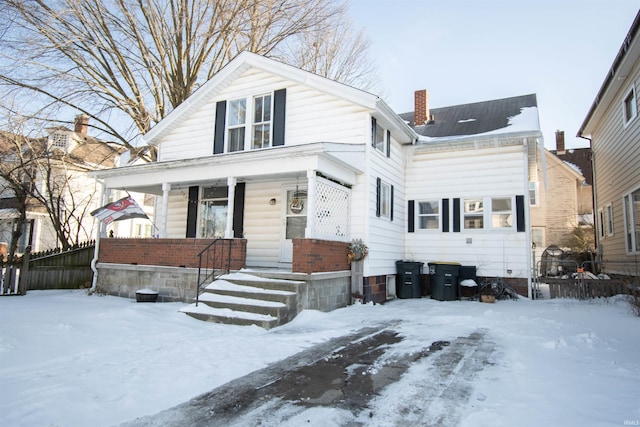 view of front of house with a porch, fence, and a chimney