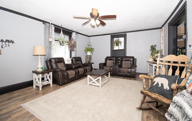 living room featuring ornamental molding, a ceiling fan, baseboards, and wood finished floors