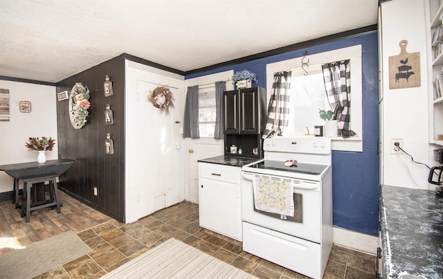 kitchen featuring dark countertops, stone finish floor, and white electric range