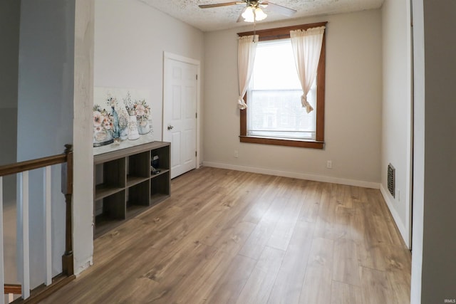 interior space featuring visible vents, ceiling fan, a textured ceiling, wood finished floors, and baseboards