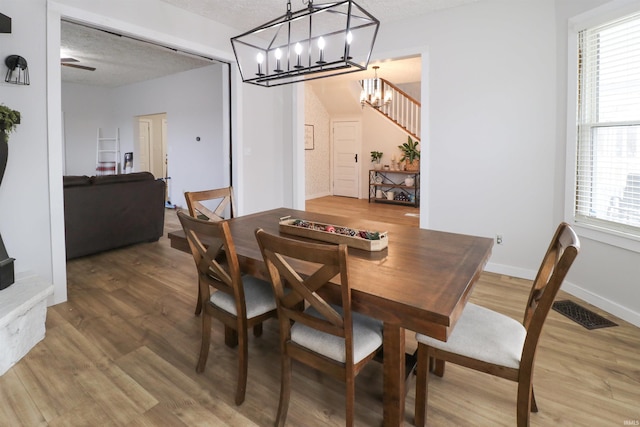 dining area with visible vents, stairway, a textured ceiling, wood finished floors, and baseboards