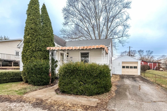 view of front facade with roof with shingles, an outdoor structure, driveway, and a detached garage