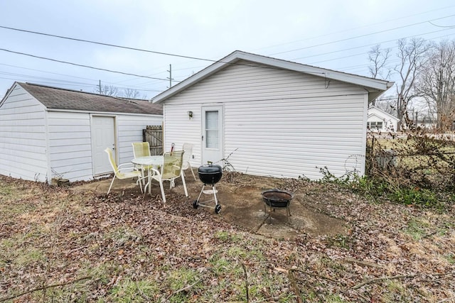 back of house with fence, a fire pit, and an outdoor structure