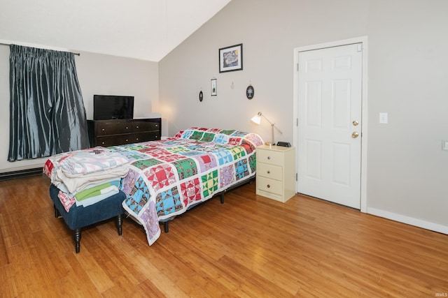 bedroom with baseboards, vaulted ceiling, and wood finished floors