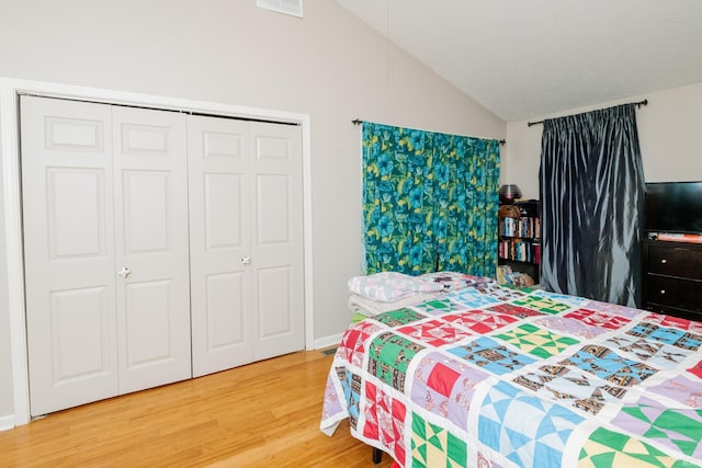 bedroom with lofted ceiling, a closet, and wood finished floors