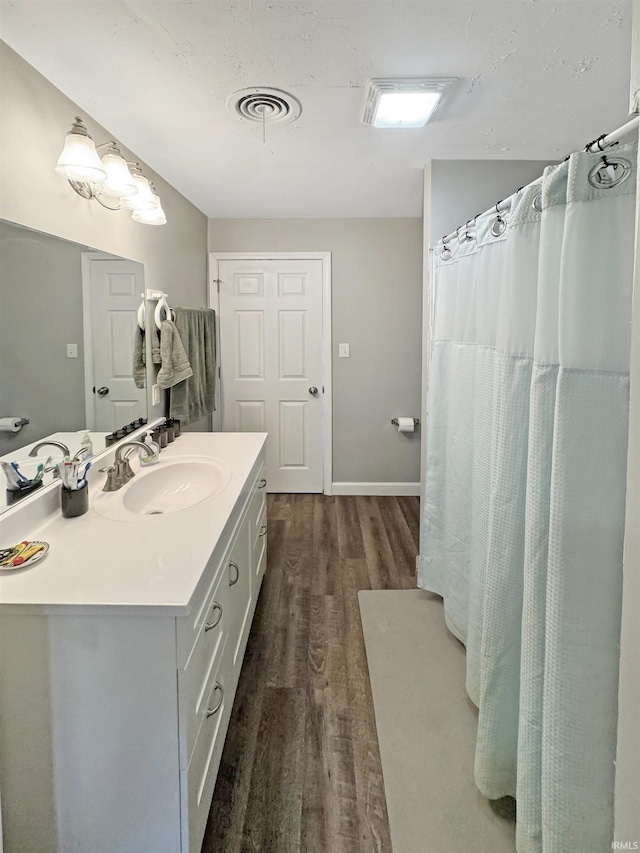 full bath with visible vents, baseboards, wood finished floors, and vanity