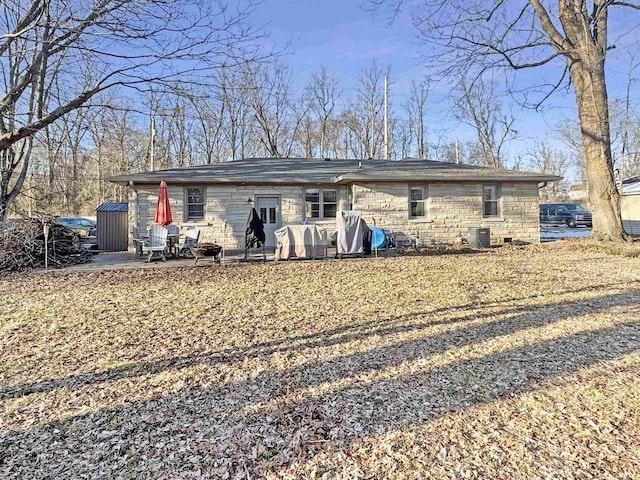 rear view of property featuring a patio, central air condition unit, and stone siding