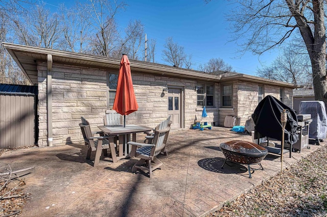 back of property with stone siding, a fire pit, outdoor dining area, and a patio