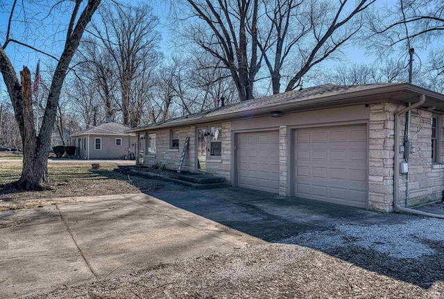 ranch-style home with stone siding, an attached garage, and concrete driveway