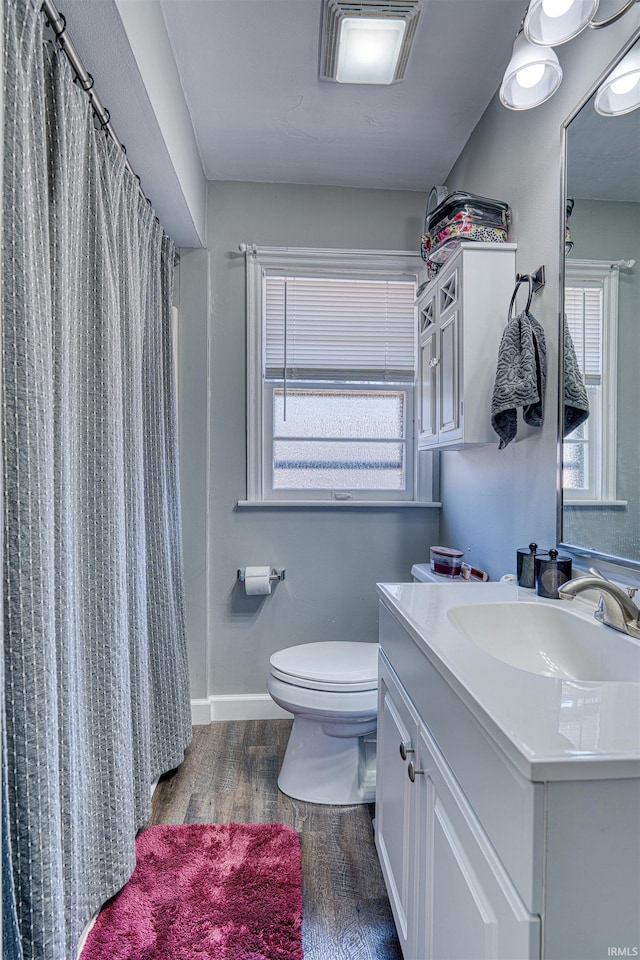 full bathroom featuring plenty of natural light, toilet, wood finished floors, and vanity