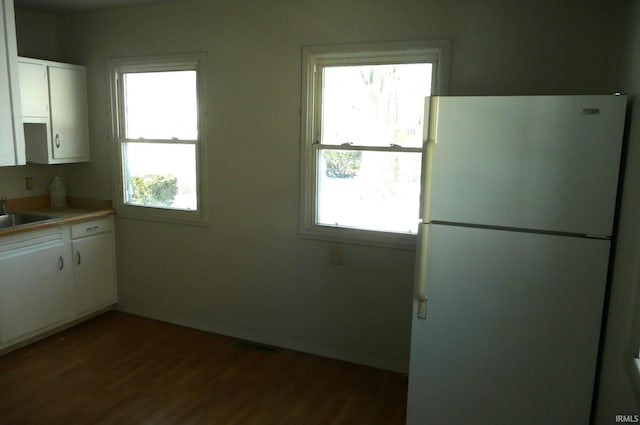 kitchen with a sink, white cabinets, light countertops, and freestanding refrigerator