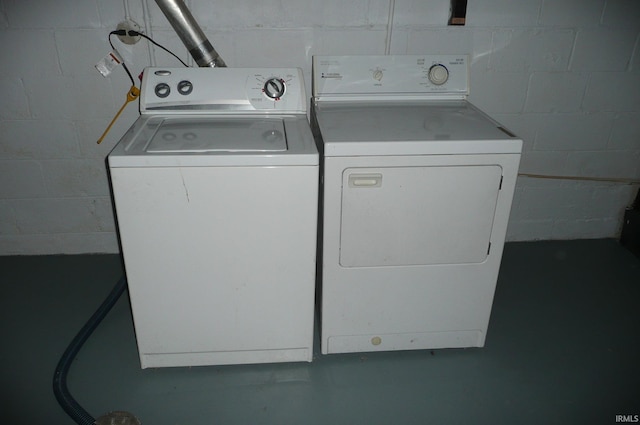 laundry room featuring concrete block wall, laundry area, and separate washer and dryer