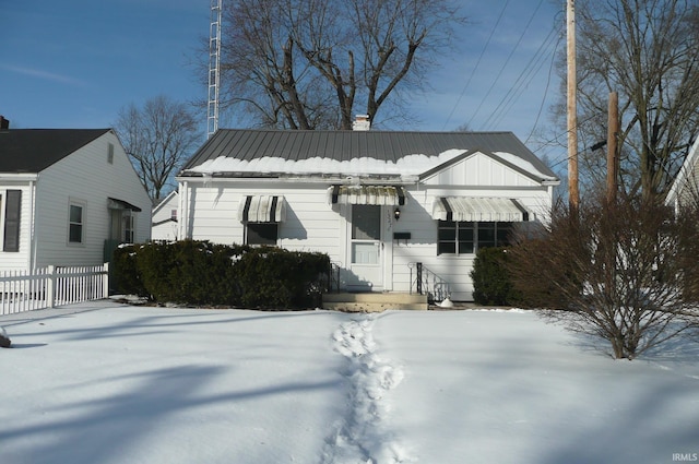 view of front of house featuring metal roof, a chimney, and fence