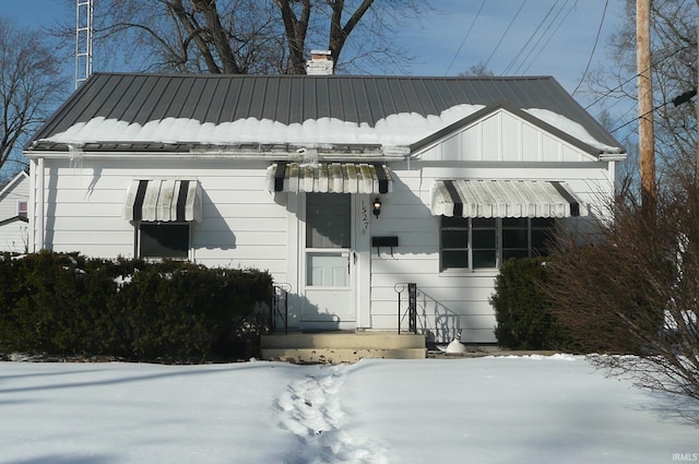 view of front facade with a chimney and board and batten siding