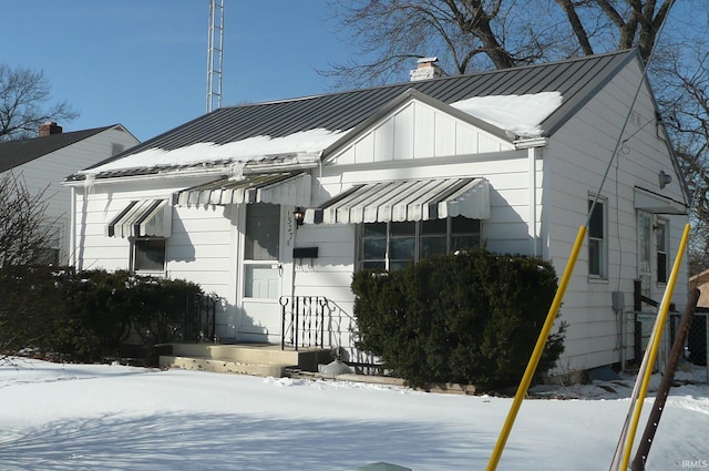 view of front of house featuring metal roof, a standing seam roof, a chimney, and board and batten siding