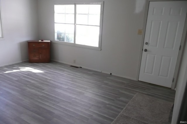 empty room featuring wood finished floors, visible vents, and baseboards