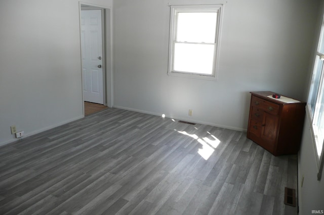 spare room featuring dark wood-style floors, visible vents, and baseboards